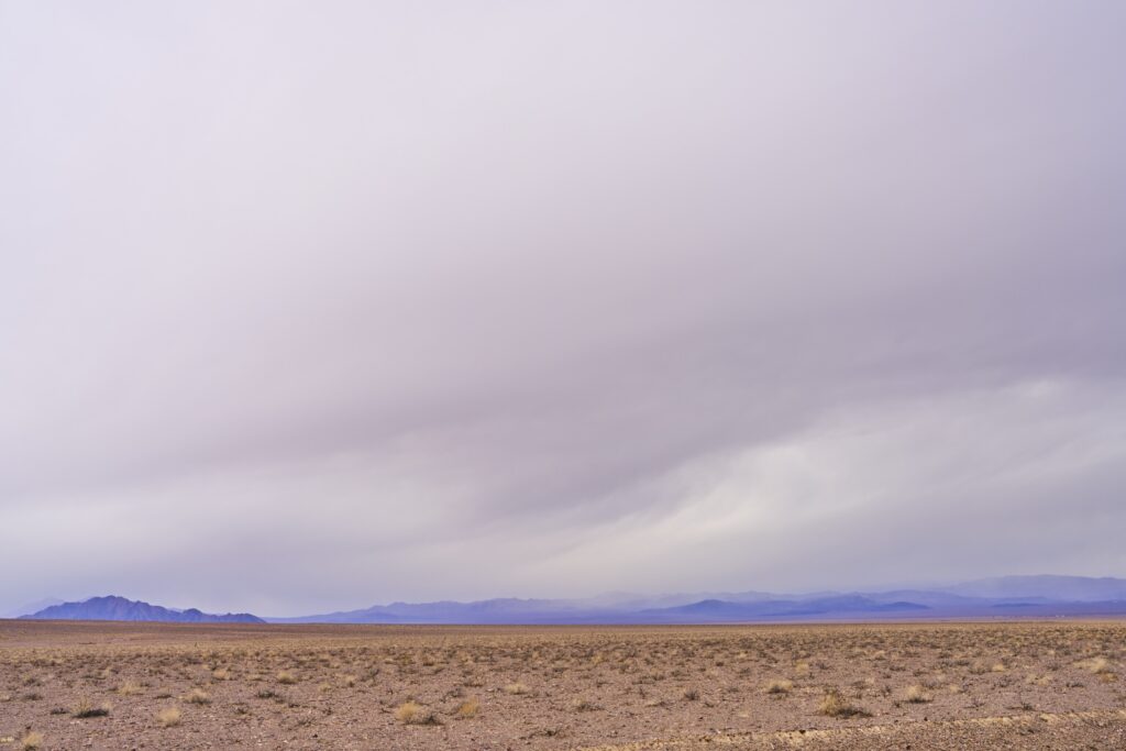 Steppenlandschaft mit Bergen am Horizont und dichter Wolkendecke