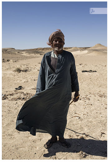 ein Beduine mit einem Stock in der Hand und einem Turban auf dem Kopf in der Wüste Ägyptens