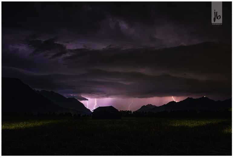 Blitze bei einem Gewitter, welches den gesamten Himmel Pink und Lila färbt