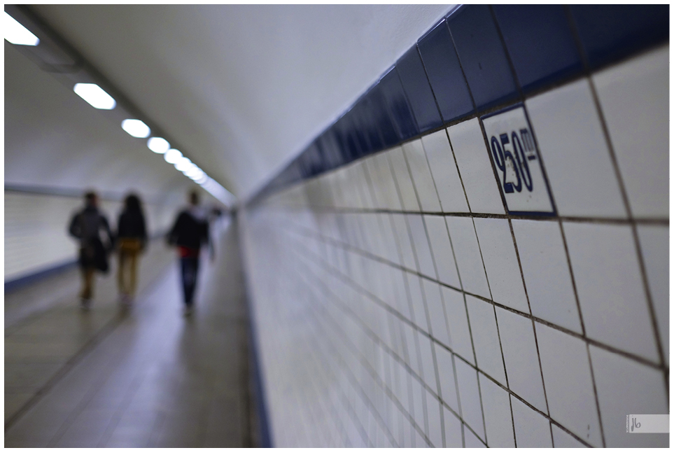 ein Gang im U-Bahngewölbe von Antwerpen, schemenhaft zu erkennen sind drei Personen