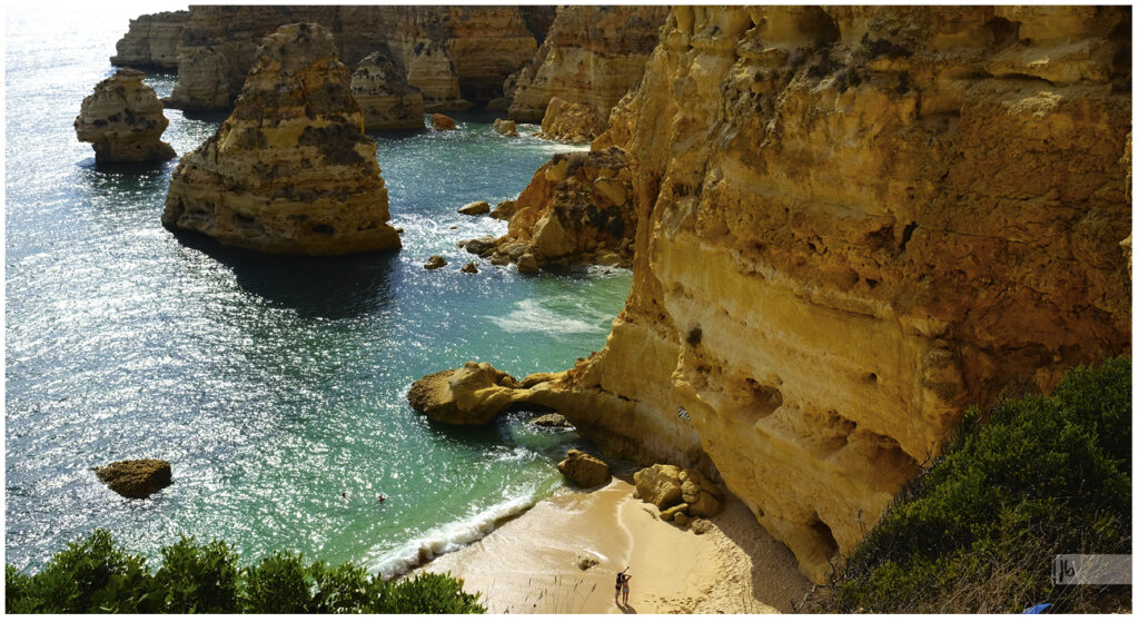 Felsformation in der Algarve mit gelbem Stein und Türkisen Wasser.