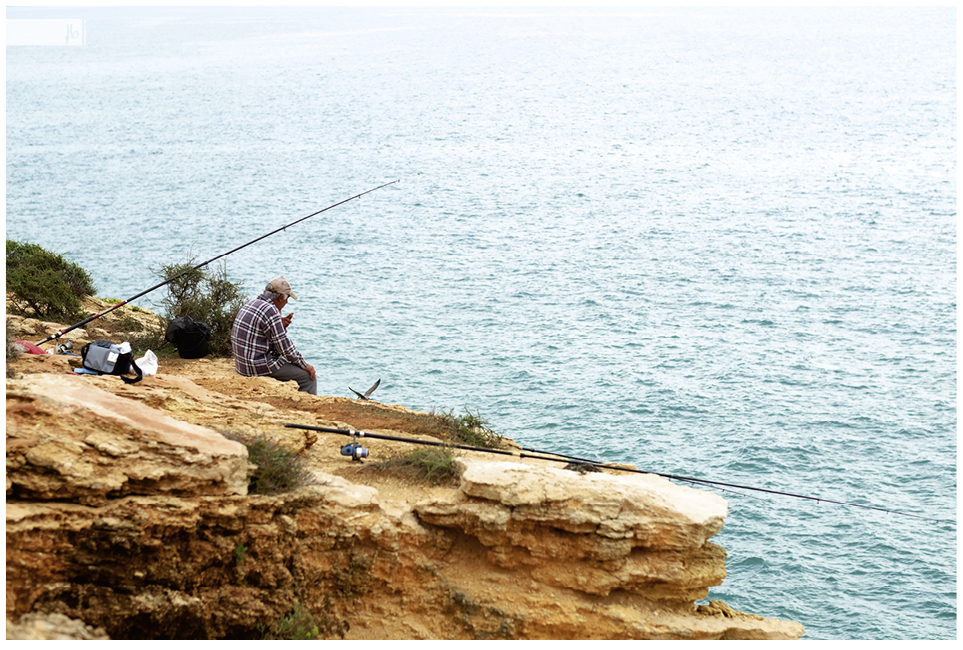 ein Angler an der Klippe sieht aufs Meer hinaus