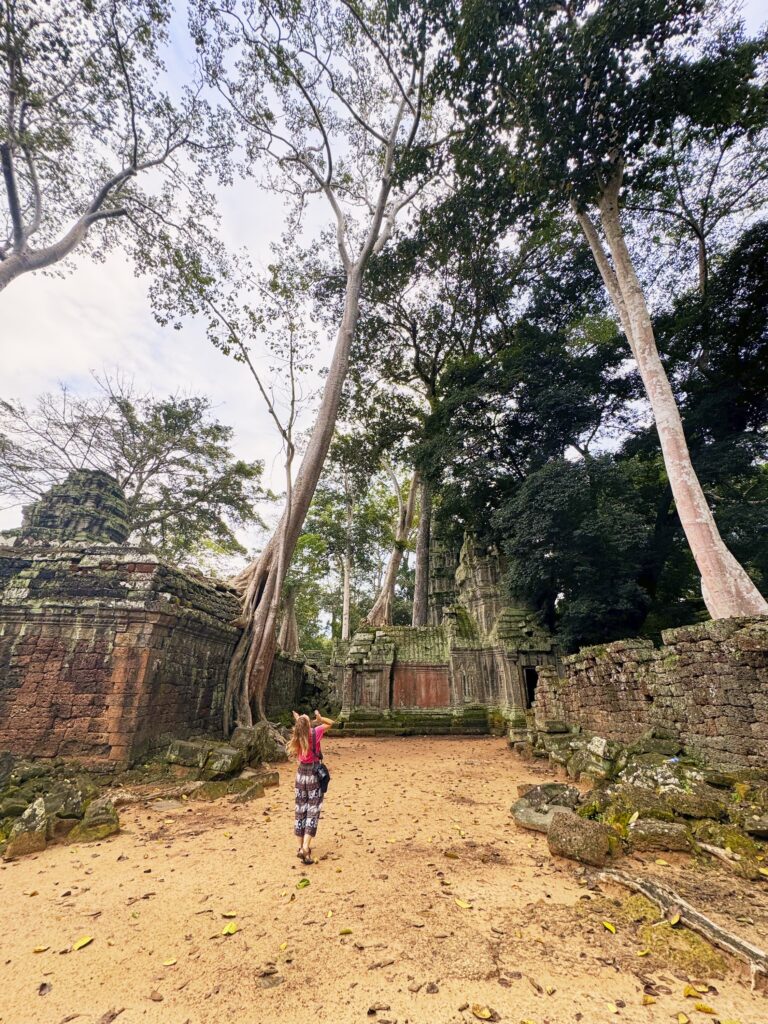 Eine Frau (ich) steht inmitten der Ruinen des Ta Prohm Tempels in Angkor Wat