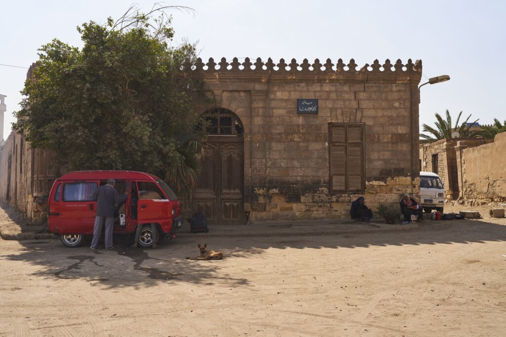 ein roter Kleinbus vor einem Backsteingebäude in der Stadt der Toten in Kairo 