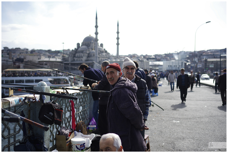 Angler und Fischer an einer Brücke in Istanbul, im Hintergrund eine Moschee