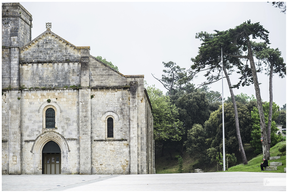 Soulac sur mer, eine Kirche mit einem großen Vorplatz und auf der Bank an der Seite sitzt ein schwarzbekleideter Mann