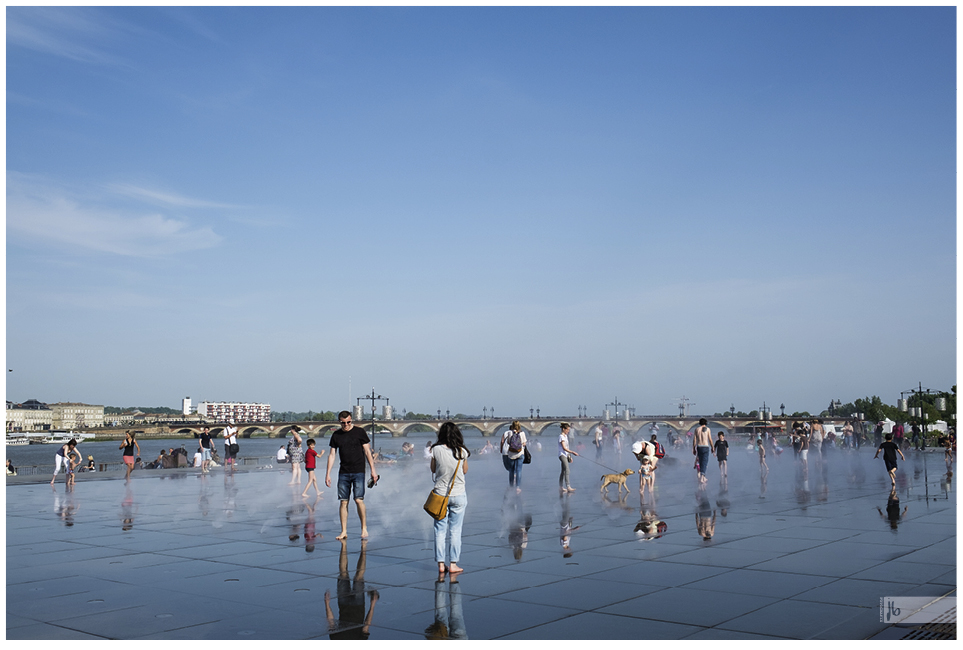 Wasserspiele in Bordeaux, viele Kinder, aber auch Erwachsene und ein Hund erfreuen sich an der nebeligen Erfrischung.