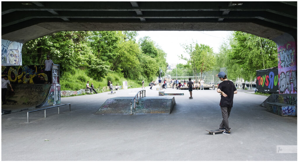 Skateboarder in Bordeaux, ein Junge im T-Shirt und Cappe steht mit seinem Skateboard am Rand und beobachtet die anderen