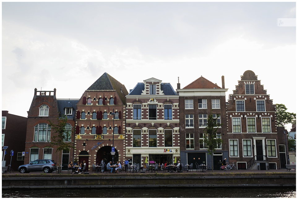 eine Häuserreihe in Amsterdam mit Cafés davor und einem Kanal