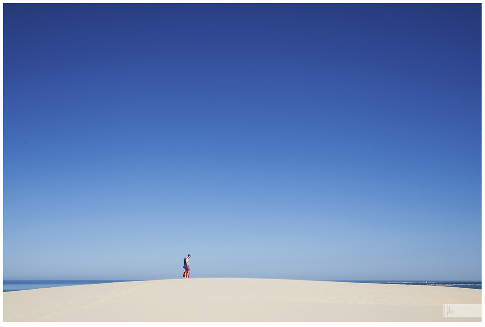 ein einzelner Mann auf der Kuppe der Dune du Pilat mit ihrem weißen Sand, einem starken Kontrast zum blauen Himmel