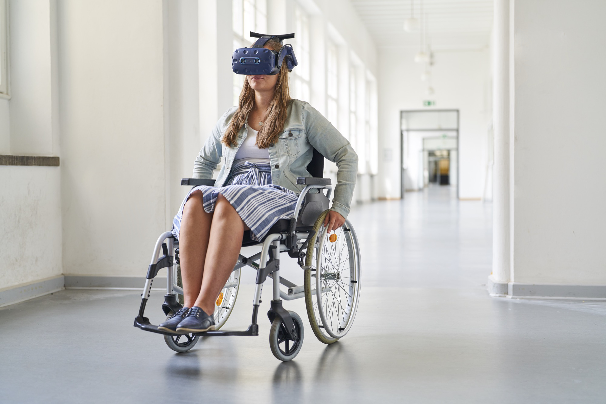 eine Studentin sitzt zu Forschungszwecken im Rollstuhl mit einer VR Brille