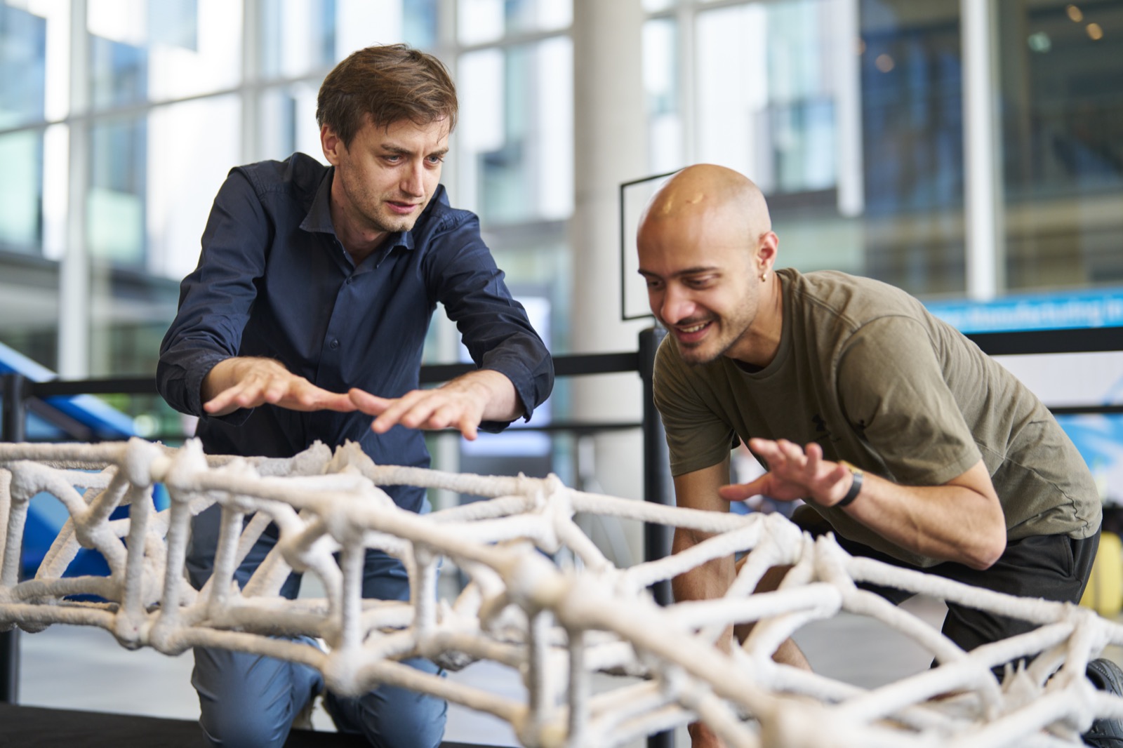 Ein Student und sein Professor begutachten die Elemente einer mit Beton gedruckten Brücke