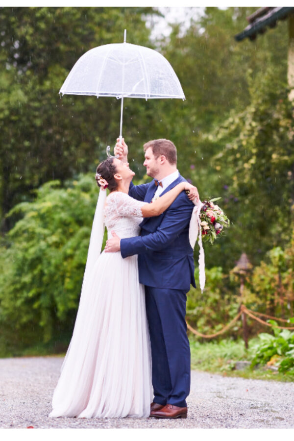 Portraits des Brautpaares bei Regen mit durchsichtigem Regenschirm auf dem Gut Sonnenhausen in Glonn bei München