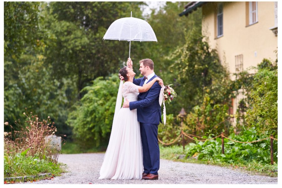 Portraits des Brautpaares bei Regen mit durchsichtigem Regenschirm auf dem Gut Sonnenhausen in Glonn bei München