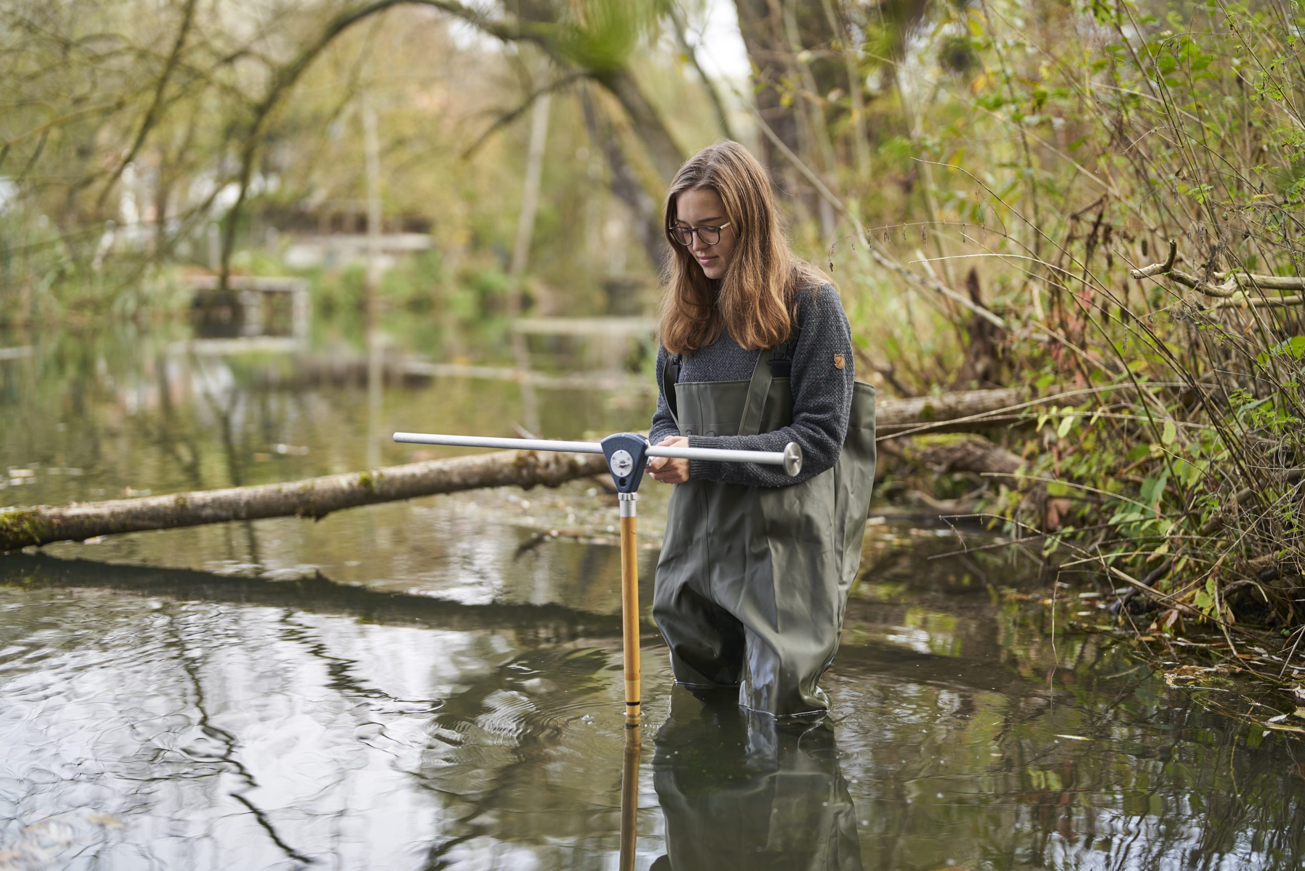 eine Forscherin in Wathosen im Wasser zur Messung von Methan